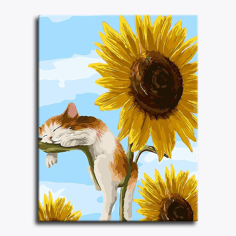Canvas print with a cat sleeping on a sunflower against a blue sky.