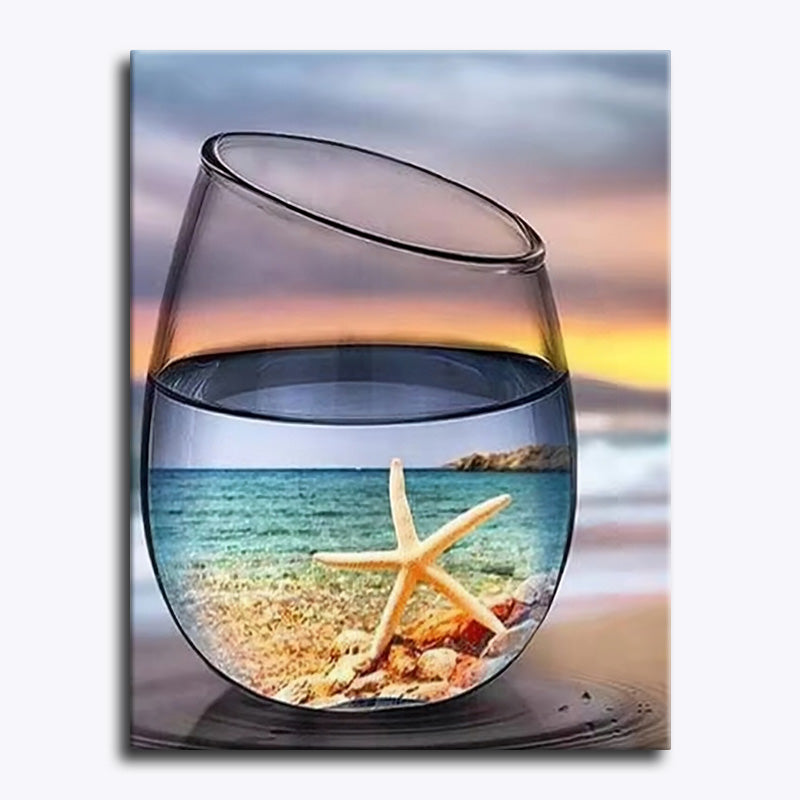 Canvas print of a glass with sand and a starfish on a beach scene.