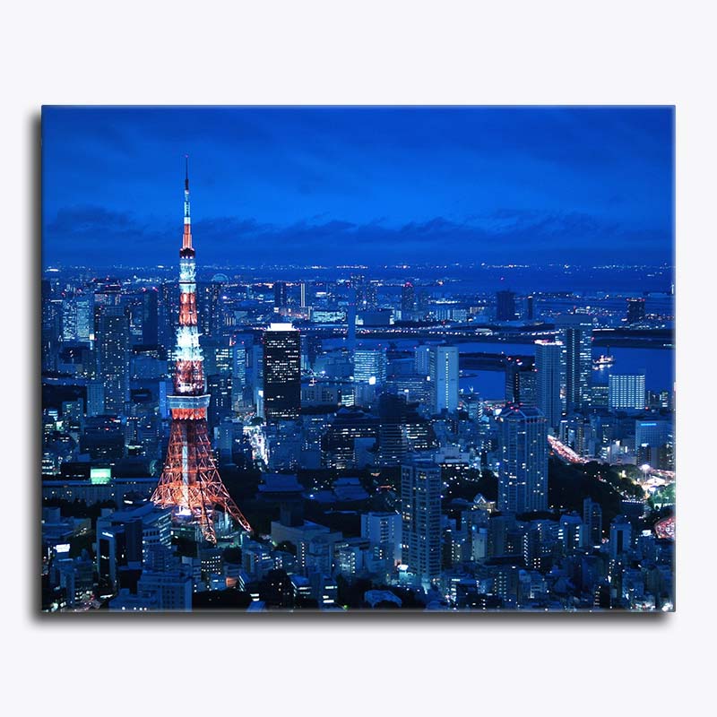 Cityscape at night with a prominent tower illuminated against a dark blue sky.