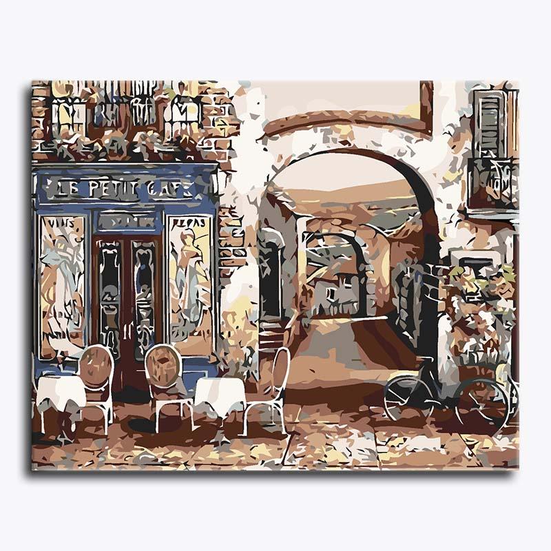 Painting of a street scene with a cafe named 'Le Petit Cafe' and people sitting on chairs.
