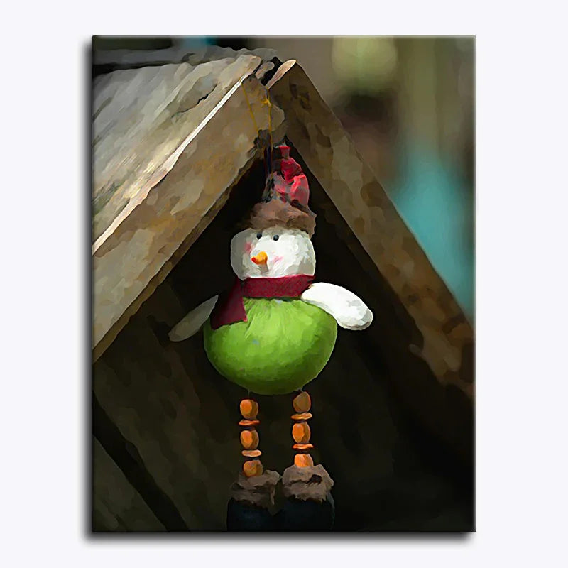Toy snowman with a green body and red scarf hanging from a wooden structure.