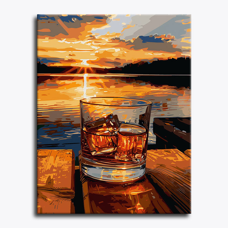 Glass of whiskey with ice cubes on a dock at sunset